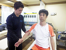 男性の腕を施術する院長